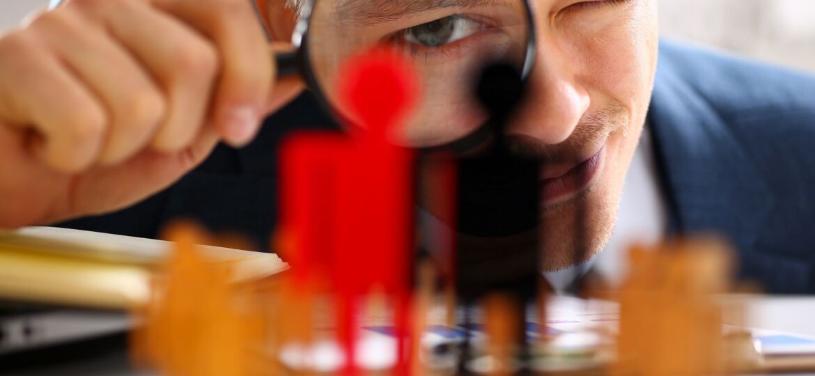 Man in suit look thru loupe on statuettes closeup